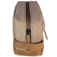 A brown canvas toiletry bag  and leather details, featuring a zipper closure and a brand logo embossed on the front.